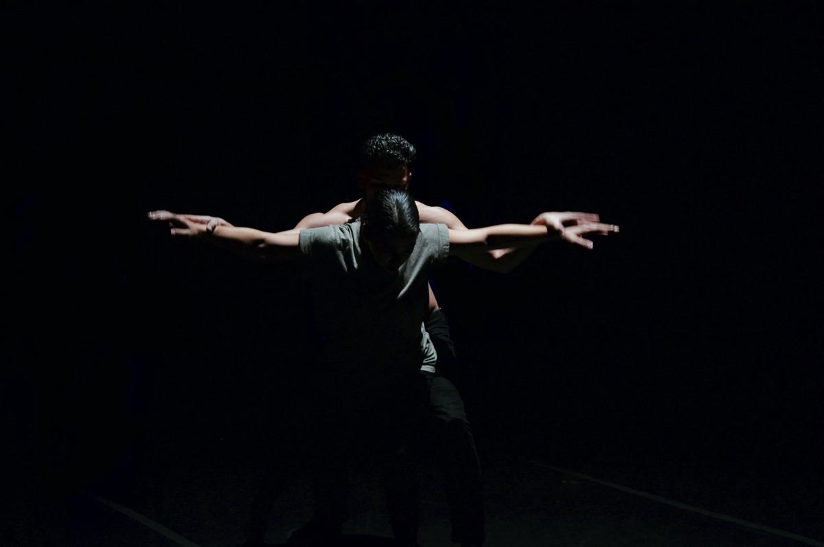 Two Jacksonville University dancers embracing on stage under the spotlight