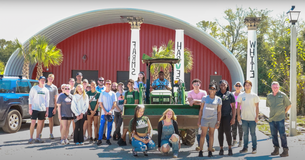 Students and workers standing in front of White Harvest Farms, smiling